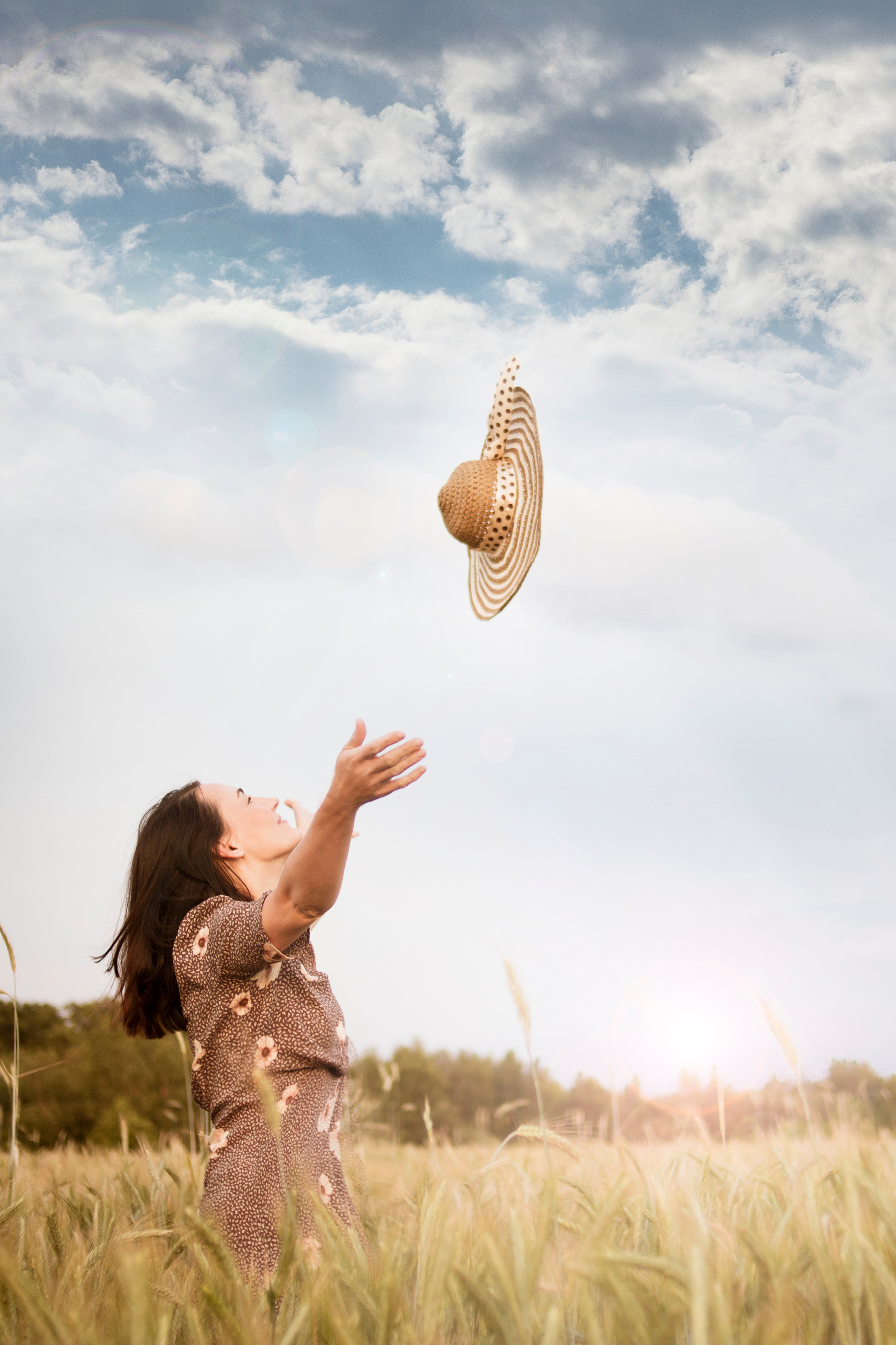 Woman Standing on Wheat Field Throwing Brown Sun Hat on the Air Under White and Blue Skies