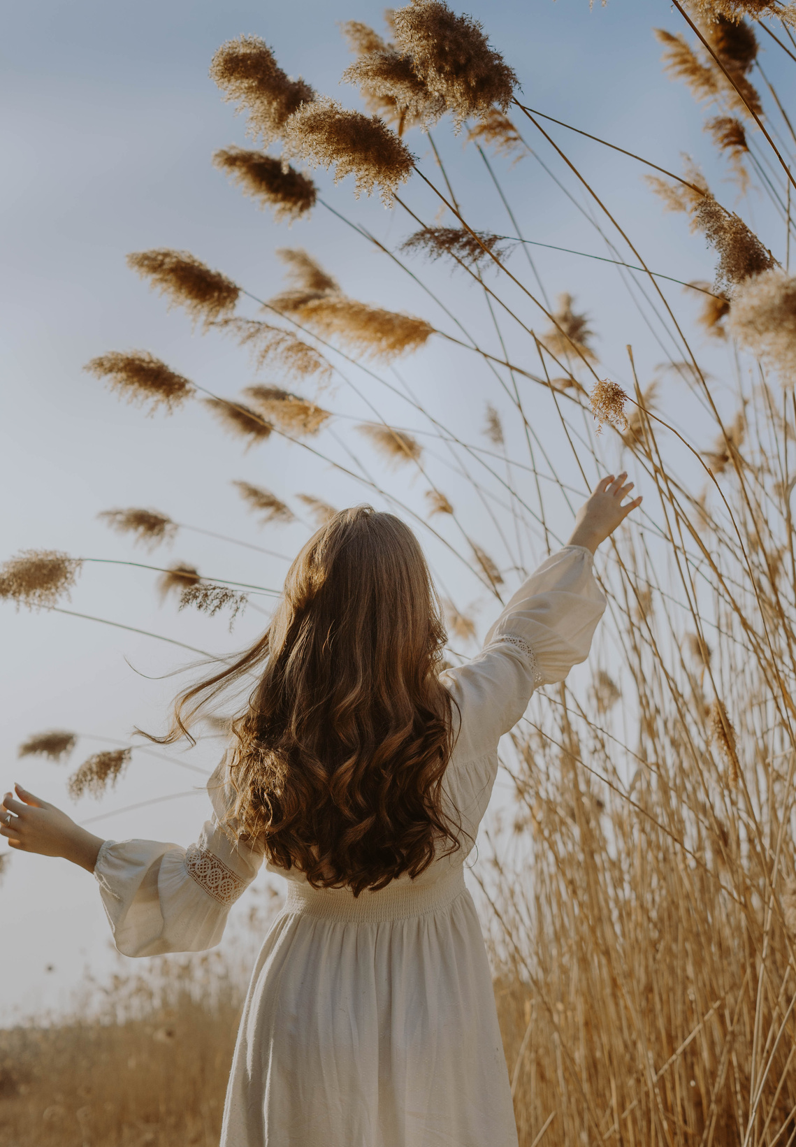 Woman in White Long Sleeve Shirt Standing on Brown Grass Field